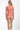 Woman wearing a coral long-sleeve top and patterned shorts on a white background
