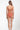 Woman wearing a coral swimsuit with thin straps on a white background