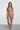 Woman wearing a pink sports bra and shorts set on a white background