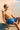 Man in blue swim shorts sitting on a beach chair at the beach.