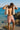 Man drying off with a towel on a beach with clear blue water and rocks.
