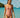 Woman in a pink swimsuit standing in clear blue water with a boat and lush greenery in the background.