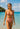 Woman in a red bikini standing in clear blue water with a boat and island in the background.