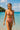 Woman in a red bikini standing in clear blue water with a boat and island in the background.