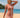 Woman wearing a pink long-sleeve rash guard and patterned shorts on a beach.