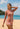 Woman wearing a pink long-sleeve rash guard and patterned shorts on a beach.