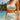 Woman in light blue sports bra and shorts standing on a beach with ocean and sky in the background