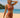 Woman in a rust-colored bikini standing on a beach with ocean and sky in the background