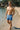 Man wearing blue patterned swim shorts standing on a beach