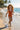 Child in an orange swimsuit running on a beach with palm trees in the background