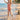 Child in a red swimsuit running on a beach with palm trees in the background