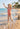 Child in a red swimsuit running on a beach with palm trees in the background