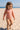 Child in a patterned swimsuit on a sandy beach with clear blue sky